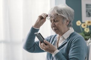 Senior woman having vision problems, she can't read the messages on her smartphone