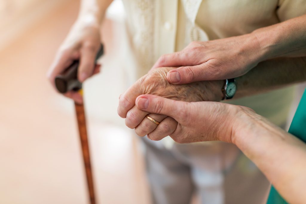 Nurse Holding hand of patient, holding a cane